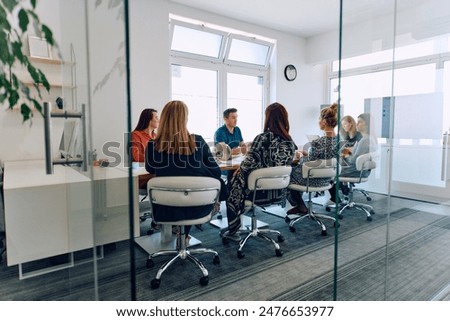 Diverse Business Team Discussing Projects in a Modern Glass Office.