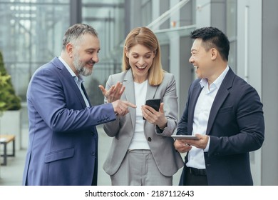 Diverse Business Team, Male And Female Business People Together Outside Office, Group Of Successful Business People Looking At Colleague's Phone, Smiling And Happy