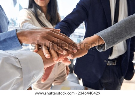 Diverse business team people joining hands together in stack expressing leadership in teamwork, trust in collaboration, integrity, unity and power in partnership success concept in office, close up.