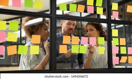 Diverse Business Team People Share Ideas Brainstorm On Corporate Project Strategy Write Ideas On Post It Sticky Notes Organize Work Process Together Look At Glass Scrum Board At Teamwork Briefing