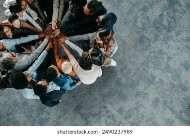 A diverse business team showing collaboration and unity with hands joined together in a team-building exercise. - Powered by Shutterstock