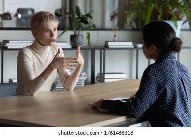 Diverse business women sit in front of each other conduct business conversation. Job interview applicant and headhunter talk. Company representative make offer to client convince buy services concept