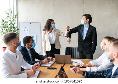 Diverse Businessman And Businesswoman Bumping Elbows Greeting Wearing Protective Face Masks During Corporate Meeting Standing In Office. Business And Covid-19 Pandemic New Rules - Powered by Shutterstock