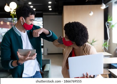 Diverse businessman and businesswoman wearing face masks touching elbows in office. social distancing in business office workplace during covid 19 coronavirus pandemic. - Powered by Shutterstock