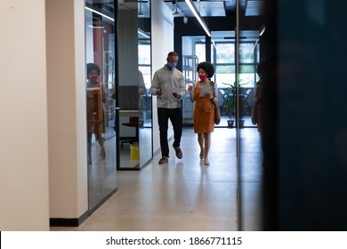 Diverse Businessman And Businesswoman Wearing Face Masks Checking Documents In Office. Social Distancing In Business Office Workplace During Covid 19 Coronavirus Pandemic.