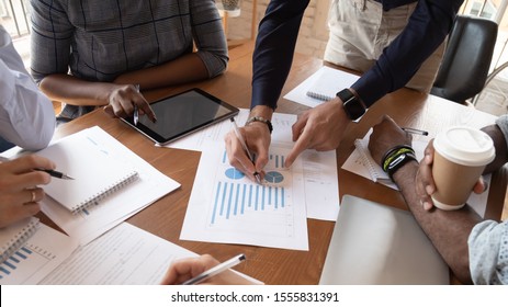 Diverse businesspeople discuss financial report in charts diagrams and graphs close up above view, business partners analysing common sales statistics presenting deal benefits at group meeting concept
