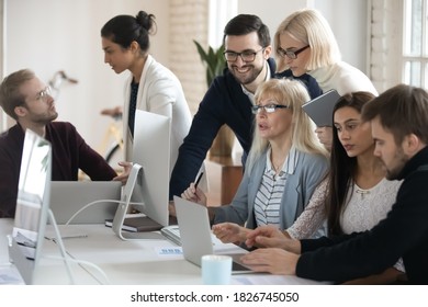 Diverse businesspeople sit at desk in office look at PC screen brainstorm on project idea together. Colleagues coworker work in groups discuss company business plan. Collaboration, teamwork concept.