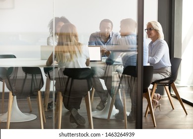 Diverse Businesspeople Sit At Office Desk Brainstorm Together Discuss Project At Meeting, Multiethnic Employees Talk Negotiate In Conference Room Share Ideas Cooperating In Boardroom At Briefing