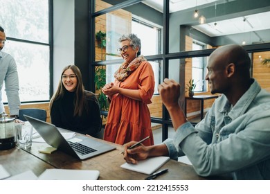 Diverse businesspeople smiling cheerfully during a meeting in a modern office. Group of successful businesspeople working as a team in a multicultural workplace. - Shutterstock ID 2212415553