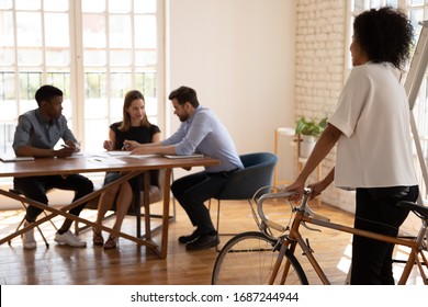 Diverse Businesspeople Talk Sit At Desk In Office, Focus On Foreground African Woman Team Leader Came To Meeting By Bicycle, Healthy Benefits Fit Lifestyle Environmental Friendly Vehicle Usage Concept