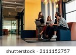 Diverse businesspeople working in an office lobby. Group of happy businesspeople having a discussion while sitting together in a co-working space. Young entrepreneurs collaborating on a new project.