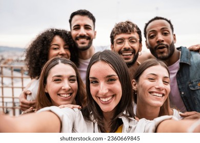 Diverse cheerful group of friends taking a selfie in a rooftop party.Multiracial young happy people smiling while taking a picture in a terrace. - Powered by Shutterstock