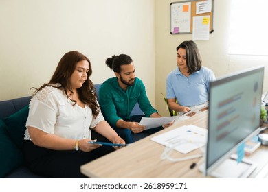 Diverse colleagues collaborating, analyzing documents and digital tablet, working together on a project in a modern office
