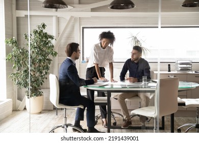 Diverse Colleagues Coworkers Gather In Boardroom Brainstorm Discuss Company Business Ideas Together. Multiracial Businesspeople Talk Consider Corporate Plans, Engaged In Team Briefing Meeting.