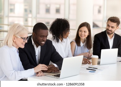 Diverse colleagues different race age businesspeople sitting together at desk in boardroom talking having pleasant informal conversation. Teamwork friendship at work between multiracial people concept - Powered by Shutterstock