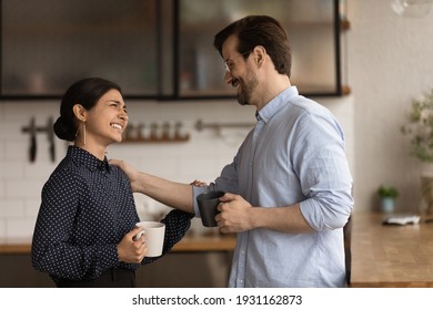 Diverse colleagues drinking coffee, chatting during break, enjoying pleasant conversation, Caucasian businessman executive congratulating Indian businesswoman with job promotion, touching shoulder - Powered by Shutterstock