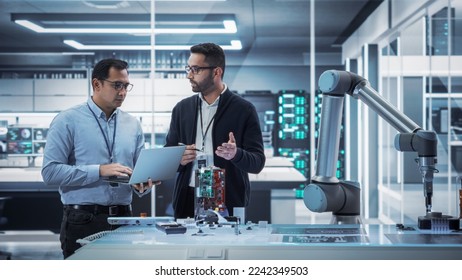 Diverse Colleagues of Industrial Robotics Engineers Experimenting With Robotic Arm. Scientists Use Laptop Computer to Manipulate and Program the Robot to Move and Put Down a Powerful Microchip. - Powered by Shutterstock