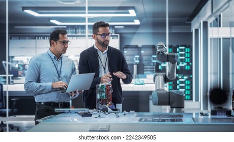 Diverse Colleagues of Industrial Robotics Engineers Experimenting With Robotic Arm. Scientists Use Laptop Computer to Manipulate and Program the Robot to Move and Put Down a Powerful Microchip. - Powered by Shutterstock