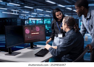 Diverse colleagues in server farm trying to protect gear from hacker stealing information. Multiethnic staff members in data center trying to fix security breach alert caused by virus