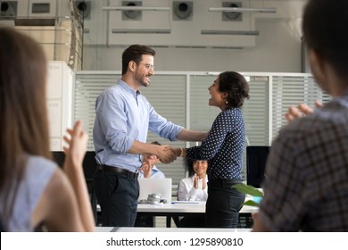 Diverse colleagues shaking hands standing in office. Company owner congratulate indian employee with reward or promotion. Millennial hindu female leader worker feels happy getting advancement at work