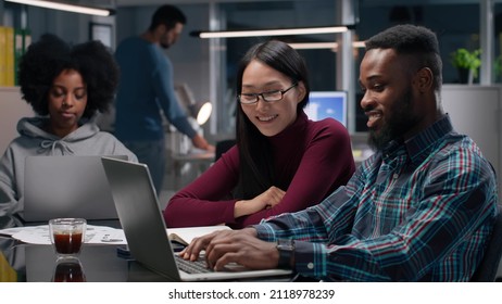 Diverse Colleagues Working On Laptop Together In Creative Office. African-American And Asian Entrepreneurs Discuss Startup Strategy In Modern Office. 