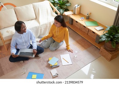 Diverse College Students Sitting On The Floor In Dormitory Room And Discussing Big Project They Were Working On