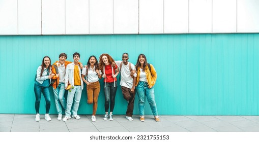 Diverse college students standing together on a blue wall - Photo portrait of multiracial teenagers in front of university building - Life style concept with guys and girls going to highschool 