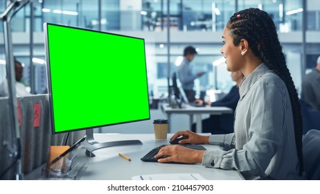 Diverse Corporate Office: Beautiful Black Female IT Technician Using Desktop Computer With Green Chroma Key Screen. Creative Software Engineer Work On ECommerce Project Marketing, Development