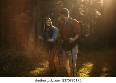 A diverse couple with backpacks and hiking poles eagerly explore the great outdoors, reveling in the serenity and beauty of their surroundings - Powered by Shutterstock