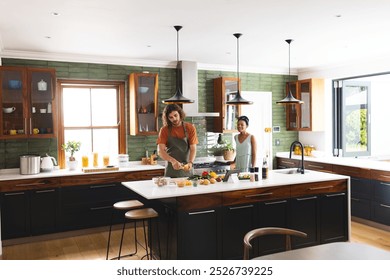 A diverse couple chops vegetables in modern kitchen, copy space. A Caucasian woman and African American man share a joyful cooking moment, unaltered - Powered by Shutterstock