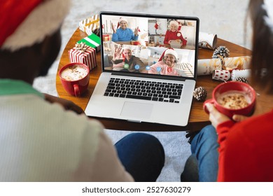 Diverse couple with christmas decorations having video call with happy diverse friends. Christmas, celebration and digital composite image. - Powered by Shutterstock