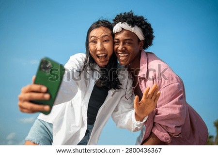 Diverse couple connected, embracing technology and social media while enjoying moments at the beach