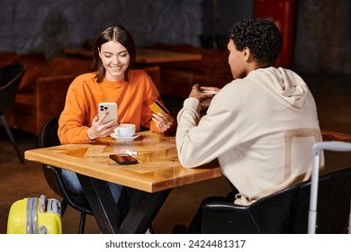 diverse couple enjoying coffee in cafe, woman holding smartphone and credit card while paying online - Powered by Shutterstock