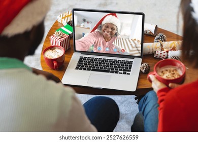 Diverse couple having christmas video call with senior african american woman. Communication technology and christmas, digital composite image. - Powered by Shutterstock