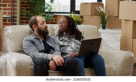 Diverse Couple Searching Decor Inspiration And Furniture On Website, Doing Online Shopping On Laptop. Moving In Apartment Bought On Mortgage Together And Decorating Flat. Handheld Shot.