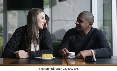 A diverse couple seated at coffee shop in conversation. Two People at cafe place listening and speaking drinking coffee - Shutterstock ID 2208307203