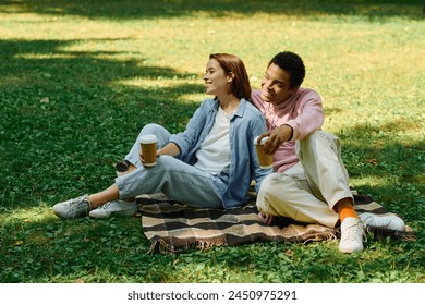 A diverse couple in vibrant attires sitting on a blanket in the grass, enjoying each others company. - Powered by Shutterstock