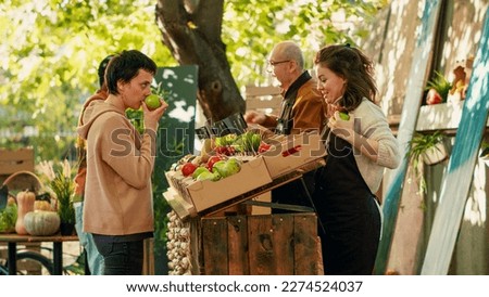 Diverse couple visiting farmers market counter with vendors, looking to buy homegrown fresh bio products from street fair. Man and woman shopping for organic vegetables at greenmarket.