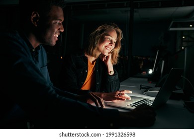 Diverse Creative Business People Working With Laptop Overtime At Night In Low Light At The Office