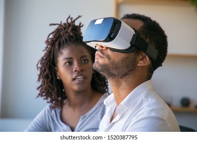 Diverse developers testing VR product. Young woman talking to male colleague wearing virtual reality glasses. Software test concept - Powered by Shutterstock