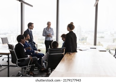 Diverse different aged business group meeting in open office space, sitting, standing in circle, talking, discussing ideas, brainstorming on project. Senior mentor, coach training team of employees - Powered by Shutterstock