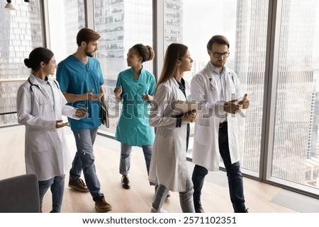 Diverse doctors actively talking while walking through hallway, looking serious, deeply engaged in their conversations, debating medical cases, lead discussion about further medical concilium topics