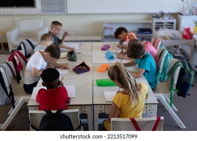 Diverse elementary school. High angle view of a diverse group of schoolchildren sitting at desks working in an elementary school classroom - Powered by Shutterstock