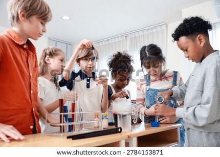 Diverse elementary students performing science experiment in classroom laboratory, exploring chemistry and teamwork. STEM education, curiosity, learning, innovation and child development concept.