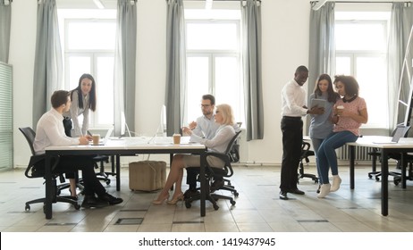 Diverse Employees Busy Working Talk And Discuss Cooperating Together In Coworking Space, Mixed Workers Speak Negotiate Sharing Ideas During Office Routine In Shared Workspace. Collaboration Concept