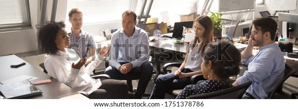 Diverse employees gathered brainstorming together\
in co working office, staff listen team leader, African woman share\
ideas, offer solutions concept. Horizontal photo banner for website\
header design