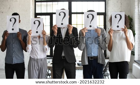 Diverse employees job candidates in row hold paper with question mark apply for vacant position in company. Unrecognized workers people before interview in office. Employment, recruitment concept.