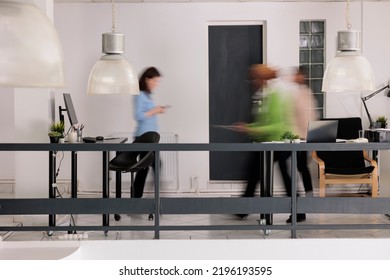 Diverse employees silhouettes walking in business coworking space, long exposure effect. Blurred busy professional workers, start up office staff workday, work rush concept, wide shot