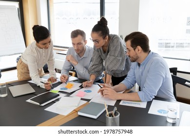 Diverse employees team coworkers discussing project strategy, working with documents, analyzing financial statistics, developing strategy, brainstorming in boardroom, teamwork and cooperation - Powered by Shutterstock