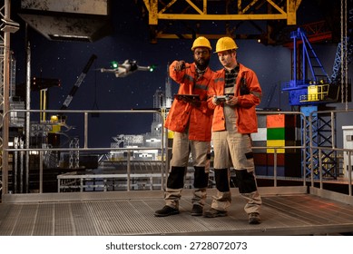 Diverse engineers colleagues using drone for remote operations and aerial mapping on offshore rig, improving logistics, planning and modern maintenance through advanced technology.